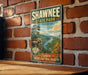 A vintage-style metal sign for Shawnee State Park, Ohio, featuring a scenic landscape with a river and mountains.