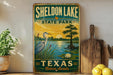 A vintage-style sign for Sheldon Lake State Park in Texas, featuring a scenic illustration of a heron, a pond, and a sunset over the lake.