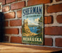 A vintage-style sign for Sherman State Recreation Area in Nebraska, featuring a scenic landscape with a sailboat on the water.