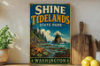 A vintage-style sign for Shine Tidelands State Park in Washington, featuring a scenic landscape with a rocky coastline, pine trees, and a starfish.