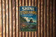 A vintage-style sign for Shine Tidelands State Park in Washington, featuring a scenic landscape with a rocky island, pine trees, and a body of water.