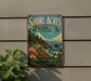 A vintage-style metal sign for Shore Acres State Park in Oregon, featuring a scenic coastal landscape with cliffs, trees, and flowers.