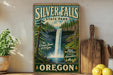 A vintage-style sign for Silver Falls State Park in Oregon, featuring a waterfall and forest scenery.