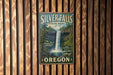 A vintage-style metal sign for Silver Falls State Park in Oregon, featuring a waterfall and forest scenery.