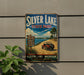 A vintage-style sign for Silver Lake State Park, featuring a scenic landscape with a red Jeep parked on a dirt road, surrounded by lush greenery.