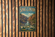 A vintage-style metal sign for Sinks Canyon State Park in Wyoming, featuring a scenic illustration of the canyon landscape.