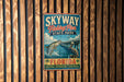 A vintage-style sign for Skyway Fishing Pier State Park in Florida, featuring an illustration of a fish jumping out of the water and a pelican.