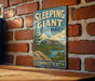 A vintage-style metal sign for Sleeping Giant State Park in Connecticut, featuring a scenic landscape with a mountain and lake.