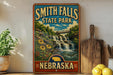 A vintage-style sign for Smith Falls State Park in Nebraska, featuring a scenic image of a waterfall surrounded by flowers and greenery.