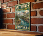 A vintage-style metal sign for Smith River State Park in Montana, featuring a scenic mountain landscape with a river flowing through it.
