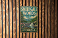 A vintage metal sign for Smithgall Woods State Park in Georgia, featuring a scenic illustration of the park's natural surroundings.