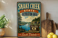 A vintage-style sign for Snake Creek State Recreation Area in South Dakota, featuring a scenic landscape with a river, mountains, and pine trees.