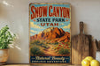 A vintage-style metal sign for Snow Canyon State Park in Utah, featuring a desert landscape with mountains and a path leading to the park.