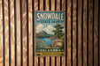 A vintage-style metal sign for Snowdale State Park in Oklahoma, featuring a scenic landscape with a lake, mountains, and a tree.
