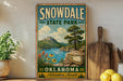 A vintage-style sign for Snowdale State Park in Oklahoma, featuring a scenic landscape with a lake, mountains, and a tree.