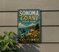 A vintage-style sign for Sonoma Coast State Park in California, featuring a scenic coastal landscape with mountains, ocean, and flowers.