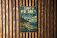 A vintage-style metal sign for South Whidbey State Park in Washington, featuring a scenic landscape with a boat on the water.