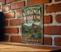 A vintage-style metal sign for the Southwest Virginia Museum, featuring a rustic image of a wooden cabin and a mill, mounted on a brick wall.