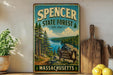 A vintage-style metal sign for the Spencer State Forest in Massachusetts, featuring a scenic landscape with pine trees, a lake, and mountains.