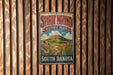 A vintage metal sign for Spirit Mound Historic Prairie in South Dakota is displayed on a wooden wall.