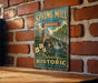 A vintage-style metal sign for Spring Mill State Park in Indiana, featuring a scenic illustration of a watermill and a waterfall.