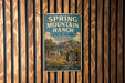 A vintage-style sign for Spring Mountain Ranch State Park in Nevada, featuring a scenic illustration of a mountain landscape and a cabin.