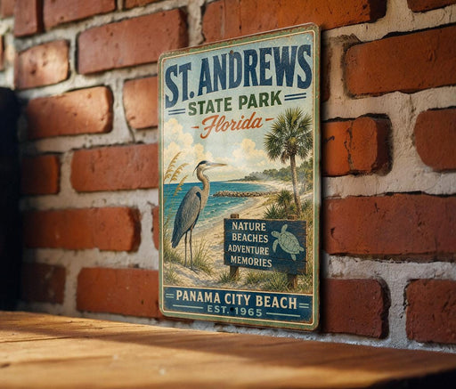 A vintage-style metal sign for St. Andrews State Park in Florida, featuring a bird and beach scenery, is displayed on a brick wall.