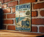 A vintage-style metal sign for St. Andrews State Park in Florida, featuring a bird and beach scenery, is displayed on a brick wall.