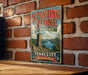 A vintage-style metal sign for Standing Stone State Park in Tennessee, featuring a scenic landscape with a lake and mountains.