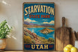 A vintage-style sign for Starvation State Park in Utah, featuring a scenic landscape with mountains, a lake, and a desert island.