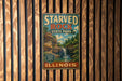 A vintage-style metal sign for Starved Rock State Park in Illinois, featuring a scenic image of a waterfall and forest.