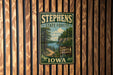 A vintage-style metal sign for Stephens State Forest in Iowa, featuring a scenic landscape with a river and forest.