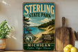 A vintage-style metal sign for Sterling State Park, featuring a scenic landscape with a lake, mountains, and pine trees.
