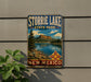 A vintage metal sign for Storrie Lake State Park in New Mexico, featuring a scenic landscape with a lake, mountains, and a pine tree.