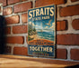 A vintage metal sign for Straits State Park, featuring a scenic image of the strait with a bridge and a bird in flight.