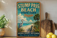 a vintage-style sign for Stump Pass Beach State Park in Florida, with a beach scene and a bird illustration. The sign is displayed on a shelf next to a wooden cutting board and a potted plant.