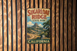 A vintage-style metal sign for Sugarloaf Ridge State Park in California, featuring a mountain landscape and the text "Sugarloaf Ridge State Park" prominently displayed.