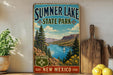 A vintage-style sign for Summer Lake State Park in New Mexico, featuring a scenic landscape with a lake, mountains, and a sailboat.