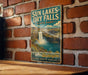 A vintage-style metal sign for Sun Lakes-Dry Falls State Park in Washington, featuring a waterfall and a mountain range.