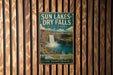 A vintage-style metal sign for Sun Lakes-Dry Falls State Park, featuring a waterfall and a scenic landscape.