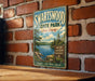 A vintage-style metal sign for Swartswood State Park in New Jersey, featuring a scenic landscape with a lake and pine trees.