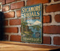 A vintage-style metal sign for Sycamore Shoals State Historic Park in Tennessee, featuring a scenic illustration of a castle and a river.