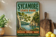 A vintage-style poster for Sycamore State Park, Ohio, featuring a scenic landscape with a lake and trees.