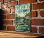 A vintage-style metal sign for Tennessee State Park hangs on a brick wall, featuring a scenic landscape with a lake and mountains.