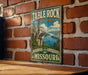 A vintage-style sign for Table Rock State Park in Missouri, featuring a scenic landscape with mountains, water, and a boat.