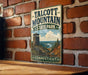 A vintage metal sign for Talcott Mountain State Park in Connecticut, featuring a scenic mountain landscape with a lookout tower.