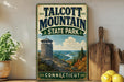 A vintage metal sign for Talcott Mountain State Park in Connecticut, featuring a scenic mountain landscape with a lookout tower.