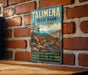 A vintage-style sign for Talimana State Park in Oklahoma, featuring a scenic mountain landscape with winding roads and autumn foliage.