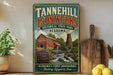 A vintage-style sign for Tannehill Ironworks, a historic ironworks in Alabama, featuring a red brick building and a mill with a waterwheel.