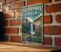 A vintage-style metal sign for Taughannock Falls State Park in New York, featuring a waterfall and lush greenery.